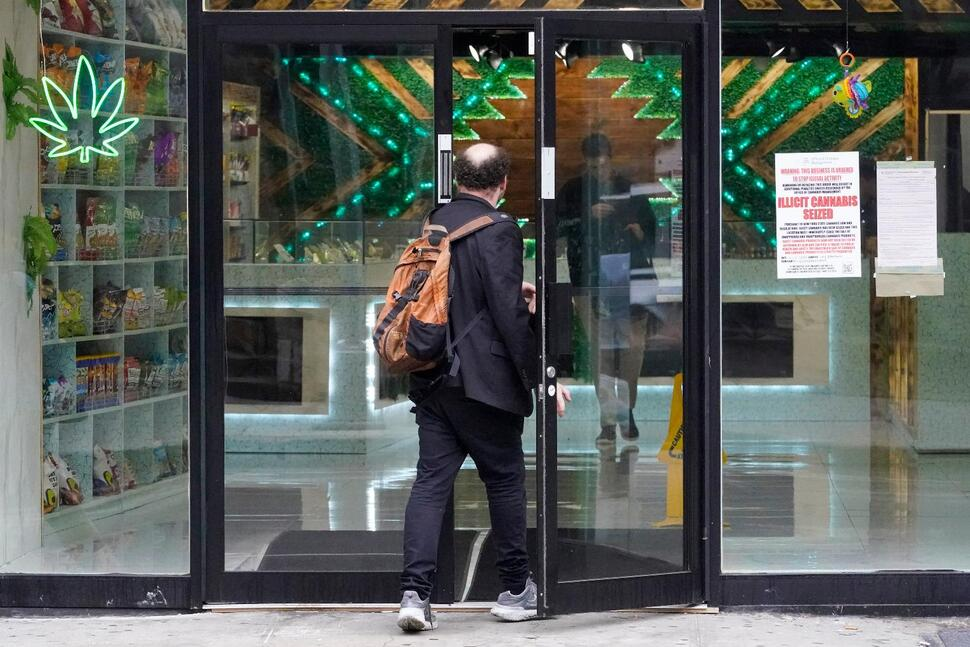 A man enters as another leaves a store with an "Illicit Cannabis seized" notice posted by inspectors in the window, Friday, June 23, 2023, in New York. New York says it's toughening up on bootleg pot shops, with a new enforcement squad heading out to the array of unlicensed stores troubling the state's fledgling legal marijuana market. "You will be caught," the governor vowed last week. (AP Photo/Mary Altaffer)

